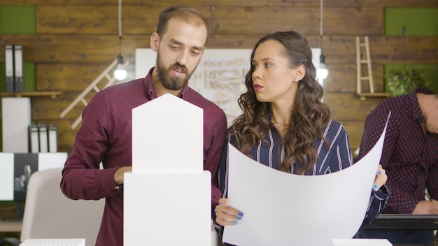 Arquiteto e designer feminino e masculino falando sobre um novo edifício no interior de um escritório moderno