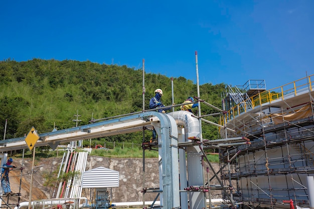 Arquiteto em trabalhadores de construção local em um duto de andaime. Andaimes extensos fornecendo plataformas para trabalhos em andamento. Homens caminhando no telhado cercados por andaimes