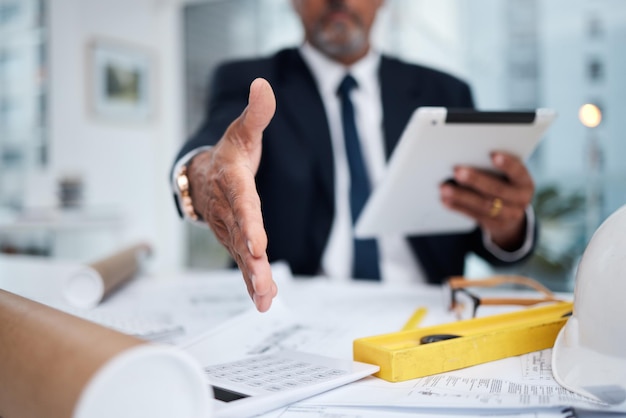 Foto arquiteto estendido à mão e um homem no escritório para um aperto de mão para saudação de boas-vindas ou negócio pov do engenheiro masculino com um tablet e gesto para negociação comercial obrigado e acordo ou confiança