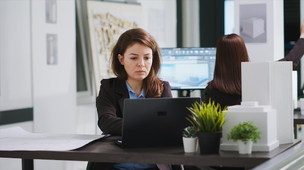 Arquiteto estudando o layout da propriedade no laptop para criar um plano