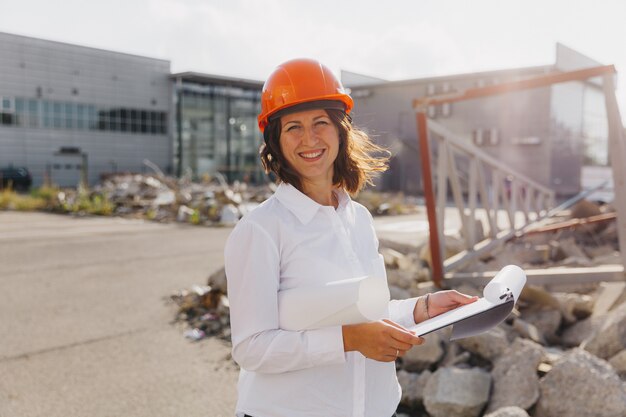 Foto arquiteto jovem e bonita na camisa branca e capacete segurando uma placa flip. mulher com capacete em uma construção em casa.