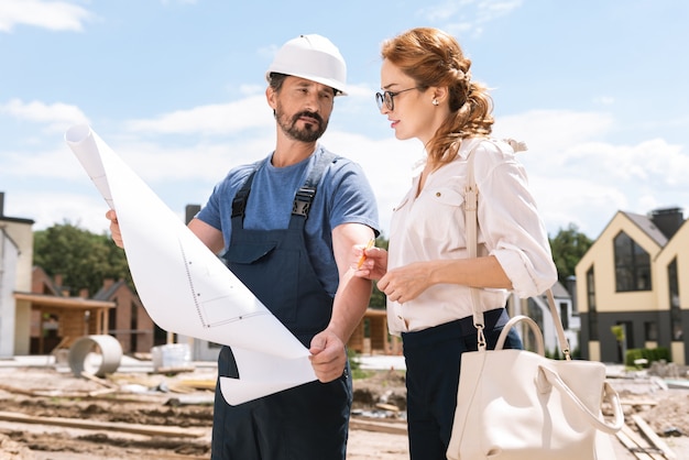 Foto arquiteto profissional inteligente segurando uma planta enquanto a mostra ao cliente