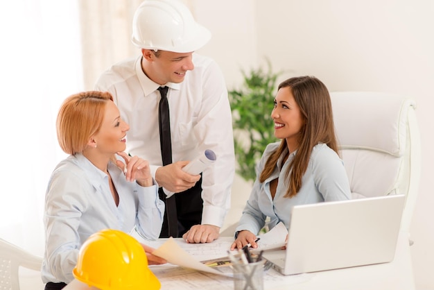 Arquiteto sorridente discutindo e olhando os planos arquitetônicos no escritório.