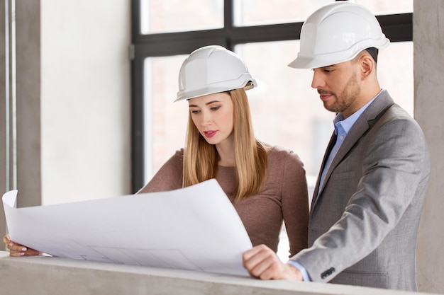 Foto arquitetos com planta e capacetes no escritório