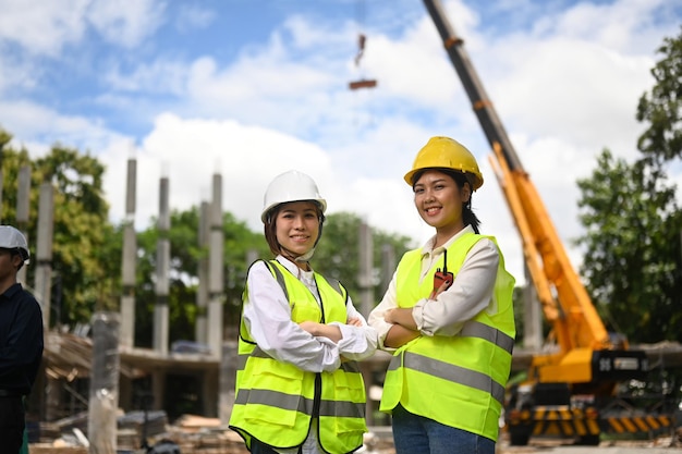 Arquitetos femininos em pé com os braços cruzados no canteiro de obras Conceito de construção do engenheiro da indústria