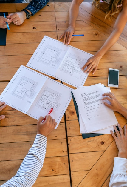 Foto arquitetos irreconhecíveis em uma reunião de trabalho olhando os planos de construção de uma casa