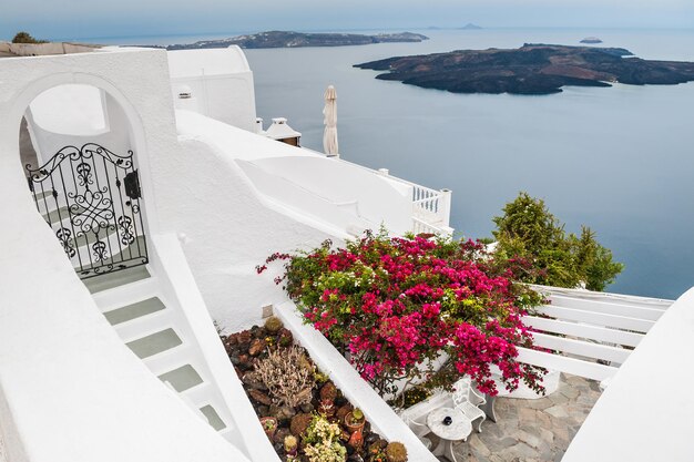 Arquitetura branca na ilha de Santorini, Grécia. Terraço com flores. Linda paisagem com vista para o mar