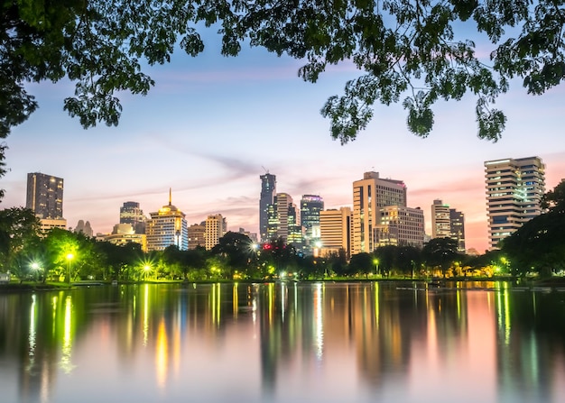 Arquitetura da cidade de arranha-céus com reflexo no lago no parque Lumpini Bangkok Tailândia