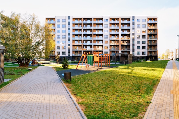 Arquitetura de fachada de casa residencial de apartamento com parque infantil e instalações ao ar livre. Céu azul ao fundo.