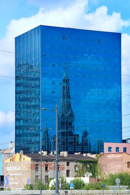 Arranha-céu em Lodz Arranha-céu alto com reflexo de igreja nas janelas de Lodz Edifício moderno com janelas iguais na cidade polonesa de Lodz
