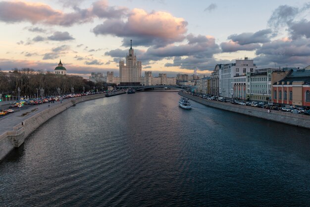 Arranha-céu soviético velho na terraplenagem de Kotelnicheskaya e na noite do rio de Moskva vista da ponte