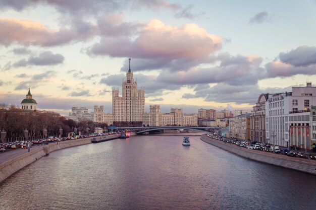 Arranha-céu soviético velho na terraplenagem de Kotelnicheskaya e na noite do rio de Moskva vista da ponte