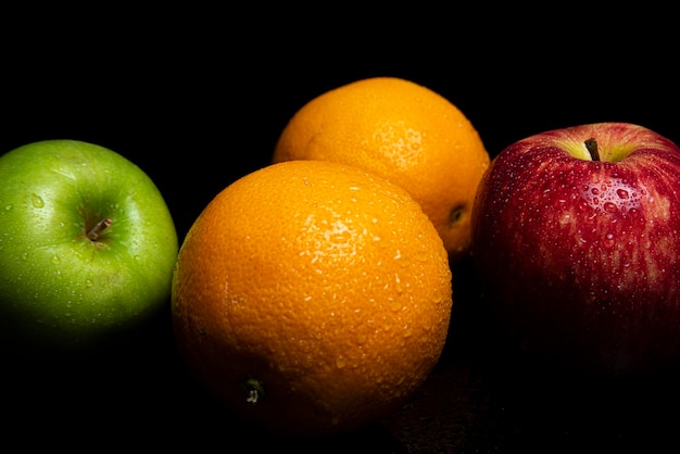 Arranjo com frutas em uma superfície preta brilhante com fundo preto