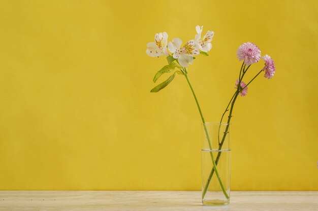 Arranjo de flores minimalista sobre uma mesa de mármore com fundo amarelo. conceção de decoração de interiores