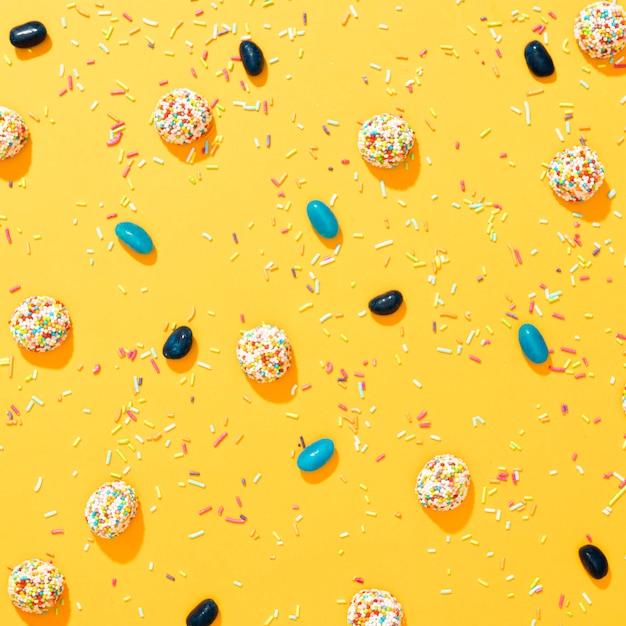 Foto arranjo liso leigo de doces coloridos diferentes em fundo amarelo