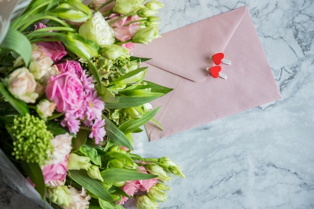 Foto arranjo plano festivo de rosas cor-de-rosa pálidas envelope branco eustoma corações cartão de férias festivo.