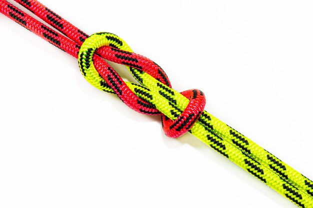 Arrecife, Hércules, cuadrado, doble o capó hermano Nudo vinculante que une dos cuerdas de colores rojo y verde. Bucle náutico utilizado para asegurar una cuerda o hilo de pescar alrededor de un objeto. Aislado sobre fondo blanco.