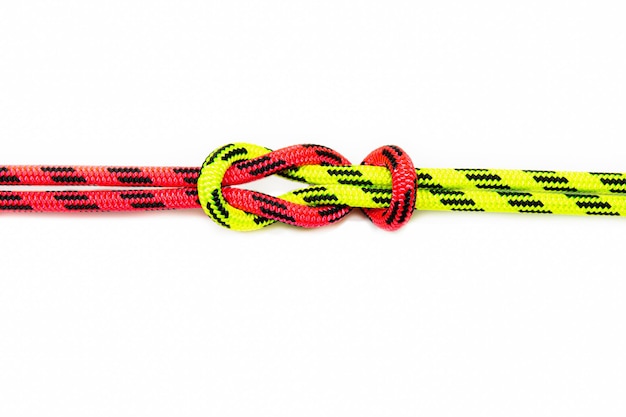 Arrecife, Hércules, cuadrado, doble o capó hermano Nudo vinculante que une dos cuerdas de colores rojo y verde. Bucle náutico utilizado para asegurar una cuerda o hilo de pescar alrededor de un objeto. Aislado sobre fondo blanco.