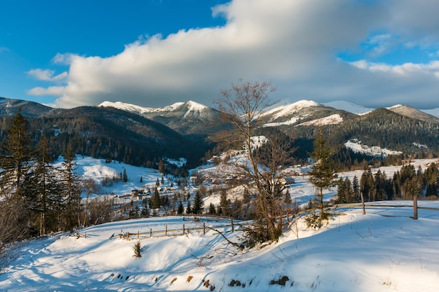 Arredores de aldeia de montanha de manhã de inverno e cume alp