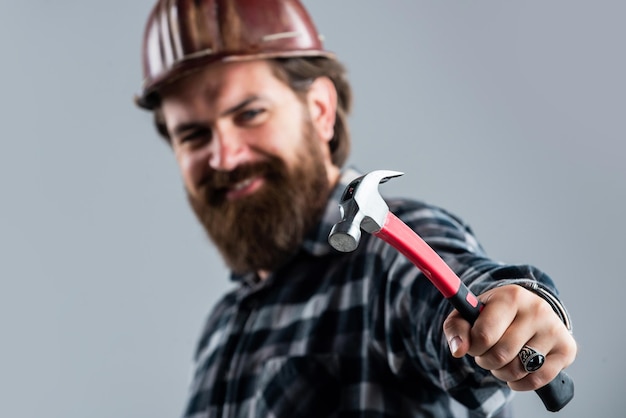 Arreglar todo usando un supervisor de equipo de seguridad en el sitio de construcción soldado confiado brutal hombre hipster hombre con casco ingeniero usar martillo trabajador de la construcción usar casco de seguridad