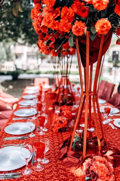 Foto arreglo de bodas de mesa roja de rosas claveles en el fondo de una mesa con mantel rojo