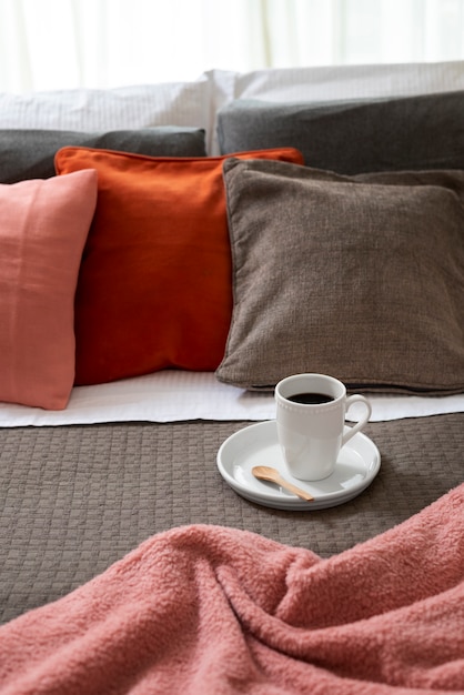 Foto arreglo de cama acogedora de alto ángulo con taza de café