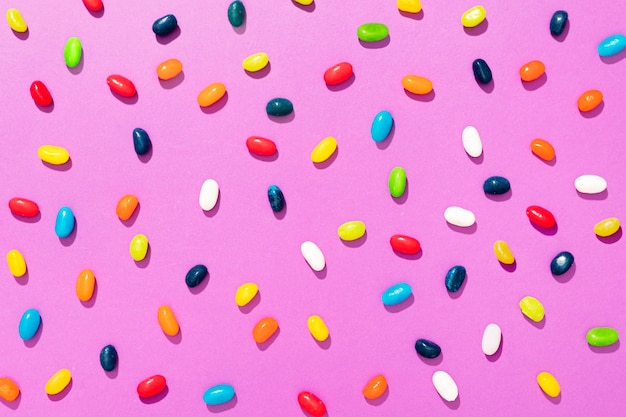 Foto arreglo de caramelos de diferentes colores sobre fondo rosa