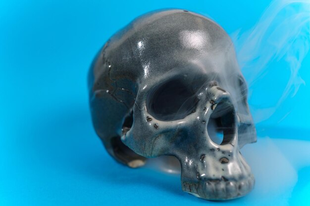 Arreglo creativo del cráneo humano contra el fondo azul Inspiración de Halloween
