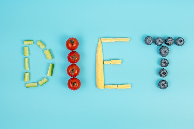 Arreglo de dieta de frutas y verduras sobre fondo azul.