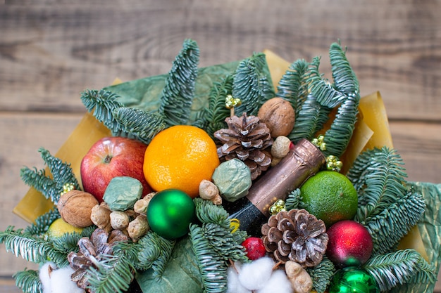 Arreglo floral de invierno festivo con ramas de árboles, manzanas, dulces, nueces y algodón naranja