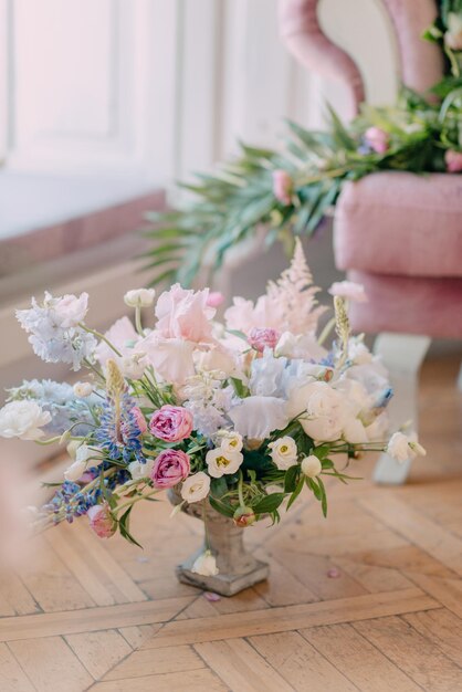 Un arreglo floral rosa y blanco se sienta en una mesa de cristal en una habitación rosa