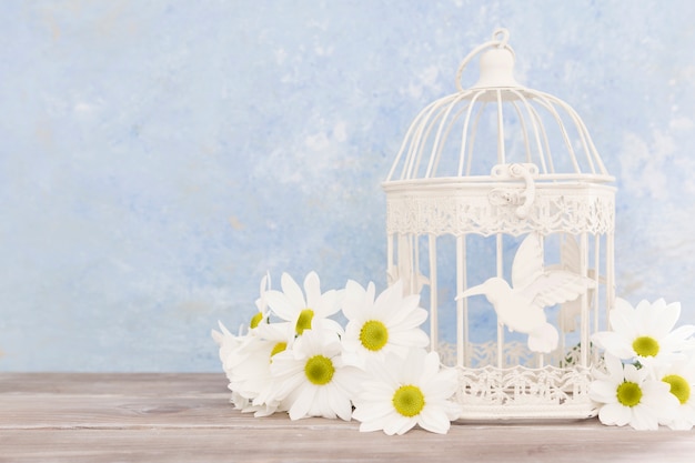 Foto arreglo con flores y una jaula de pájaros
