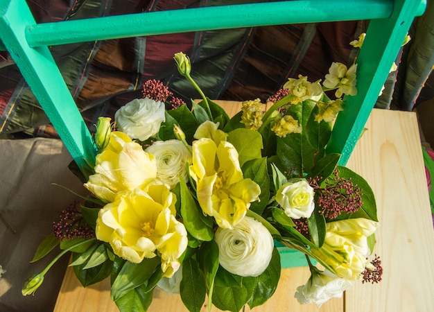 Arreglo de flores de primavera en una caja de madera verde con un travesaño