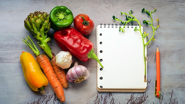 Arreglo gratuito de fotos de verduras con el bloc de notas vacío