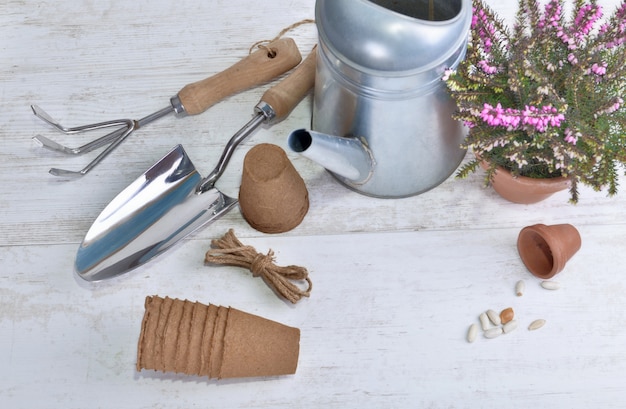 Foto arreglo de herramientas de jardinería y plantas en una mesa blanca