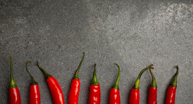 Arreglo de pimiento rojo sobre el fondo gris. Vegetal picante de ingrediente fresco para cocinar su comida.