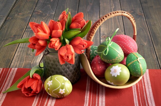 Foto arreglo de semana santa con tulipanes naranjas y huevos pintados.