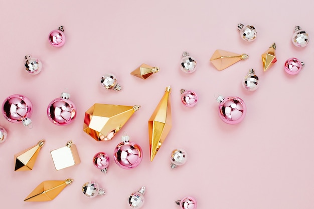 Arreglo de vacaciones Flat Lay con elegantes bolas brillantes de Navidad y cristales de oro sobre fondo rosa pastel. Endecha plana, vista superior