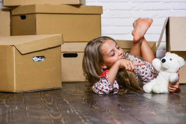 Arrendar un cambio de imagen de estilo de vida niño feliz caja de cartón Concepto de mudanza nuevo apartamento compra de nueva habitación Cajas de cartón mudarse a una nueva casa niña feliz con juguete