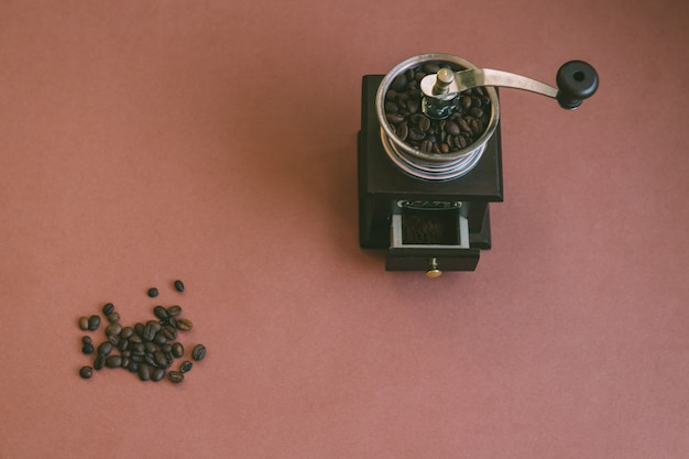 De arriba hacia abajo, una foto vintage y atmosférica de un puñado de granos de café junto con un molinillo de café de madera manual en estilo retro