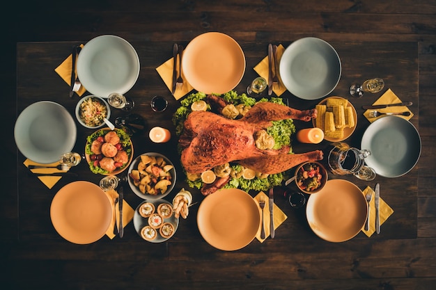 Arriba, arriba, foto de alto ángulo de grandes bebidas de pavo relleno asado al horno, guarnición de comidas, decoración vegetal, platos vacíos, cena, praparartion, dos velas encendidas en la sala de estar sin gente en el interior