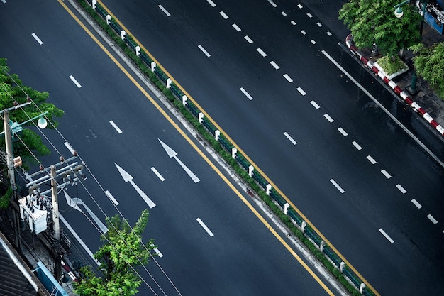 Arriba de la carretera asfaltada de dos vías con señal de tráfico de flechas en la ciudad