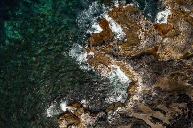 Desde arriba de la costa del océano con ásperas olas de agua clara a la luz del día