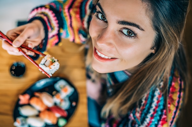 Desde arriba Crop mujer comiendo sushi