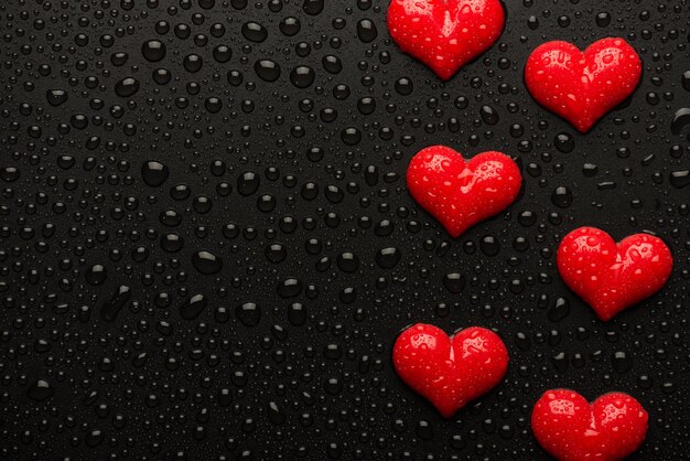 Arriba por encima de la sobrecarga vista de cerca imagen fotográfica de corazones rojos sobre fondo negro con gotas