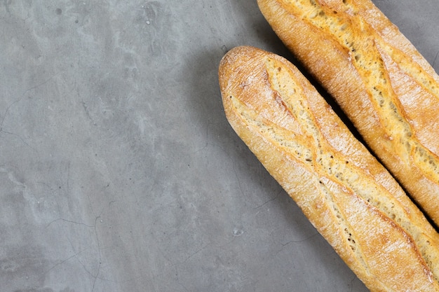 Desde arriba, foto de pan baguette francés sobre fondo de hormigón gris diagonal copyspace para texto