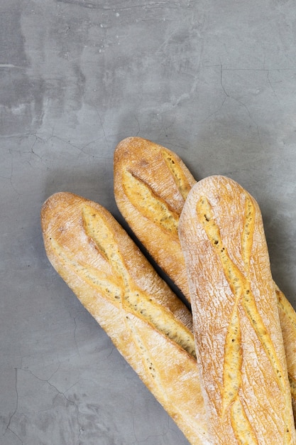 Desde arriba, foto de pan baguette francés sobre fondo de hormigón gris diagonal copyspace para texto