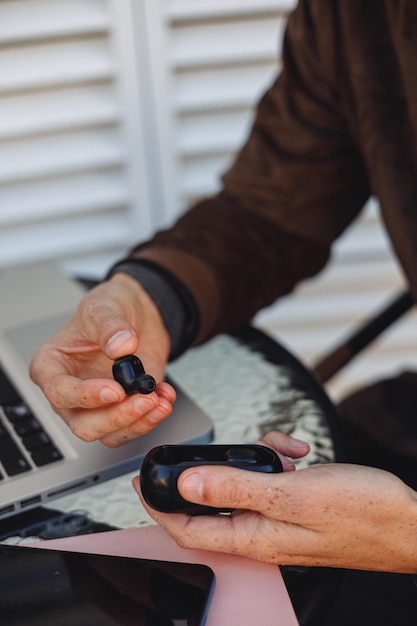 Foto desde arriba del hombre de cultivo con auriculares inalámbricos en caso de café callejero