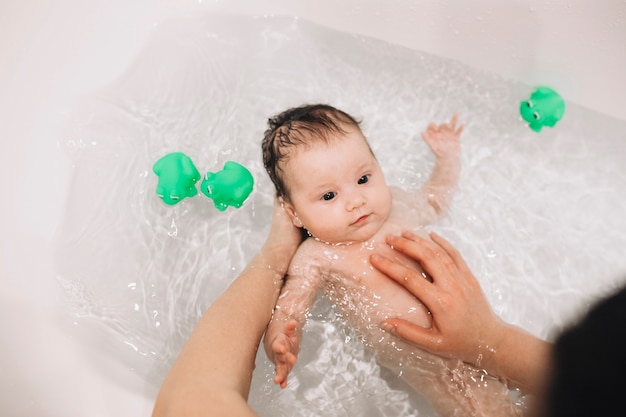 Foto desde arriba, las manos lavando al bebé
