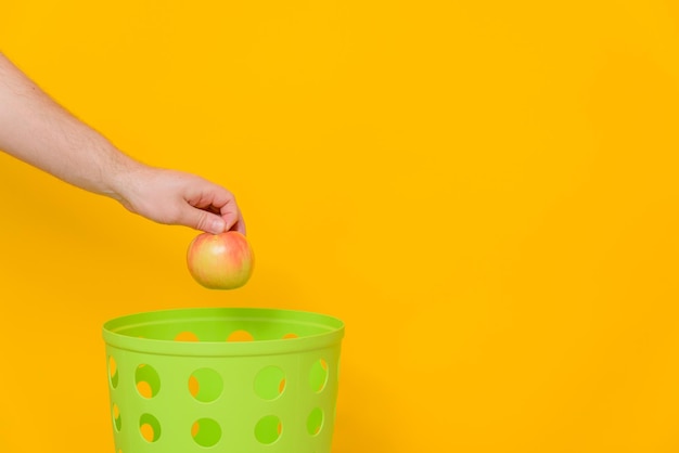 Se arroja una manzana madura entera a un bote de basura verde